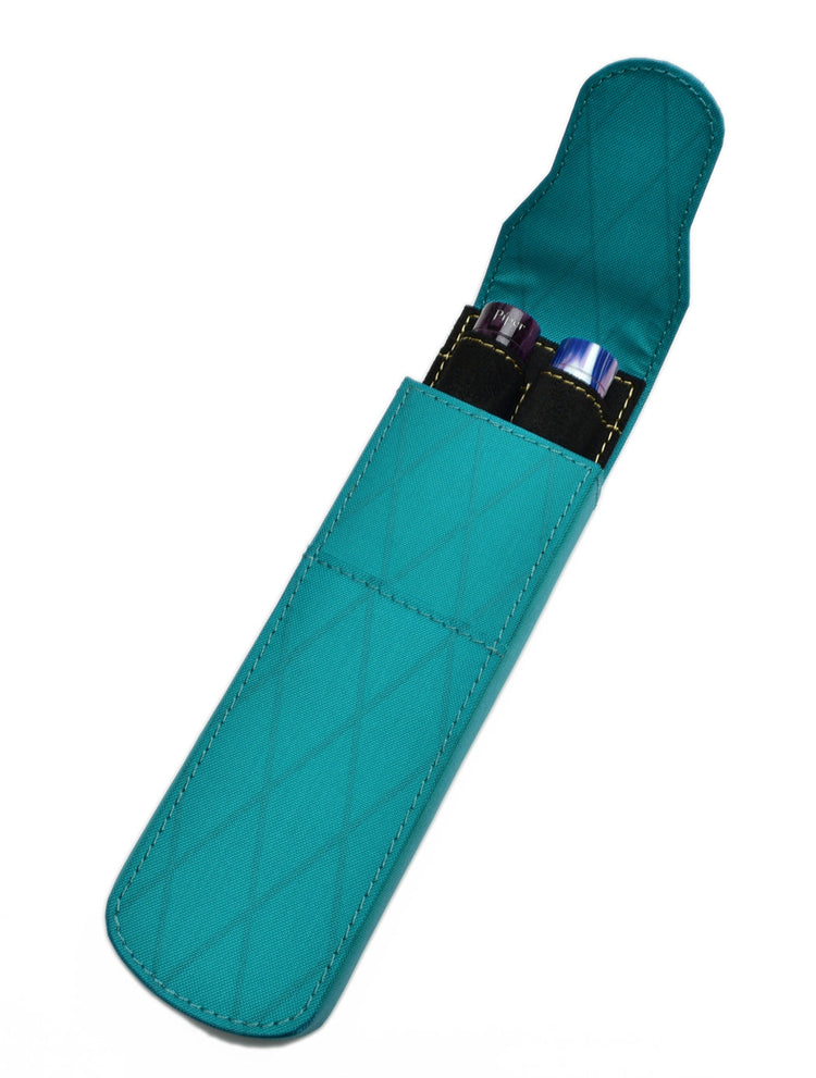 Teal fabric pen case with a diamond-stitched pattern, open to reveal two pens with visible pen caps, one purple and one blue, inside black interior slots.
