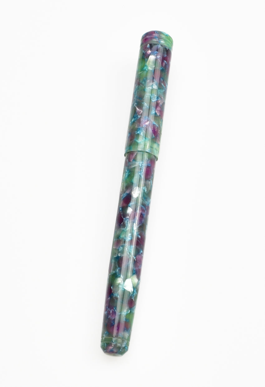 A closed Piper Trading Co. Franklin-Christoph Model 20 Fountain Pen - Scottish Heather NOS, featuring a vibrant marbled pattern in green, blue, purple, and white Scottish Heather acrylic, displayed on a white background.