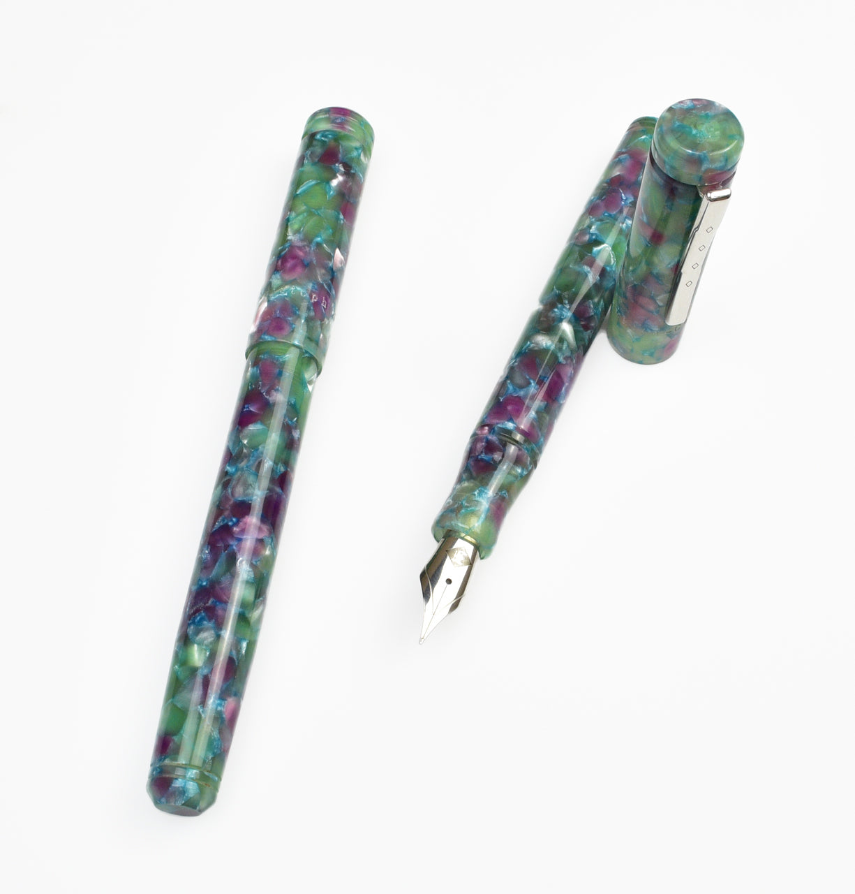 Two marbled, multicolored fountain pens—one capped and one uncapped—are displayed on a white background. These Piper Trading Co. Franklin-Christoph Model 20 Fountain Pens in Scottish Heather NOS feature vibrant swirls of green, purple, pink, and blue acrylic.
