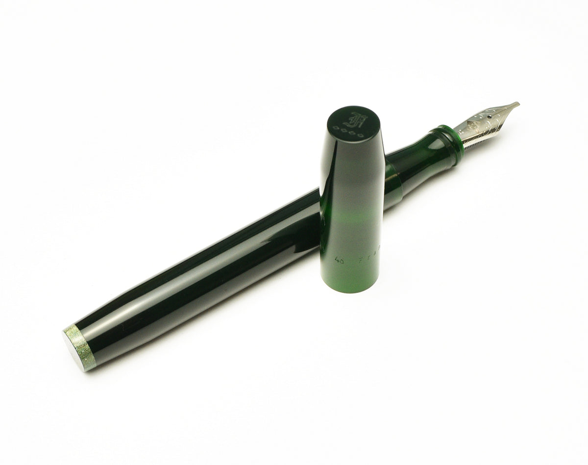 A dark green Franklin-Christoph Model 46L Fountain Pen - Emerald DC Green with its cap removed, showing the metal nib and a sparkling green base with visible block threads.