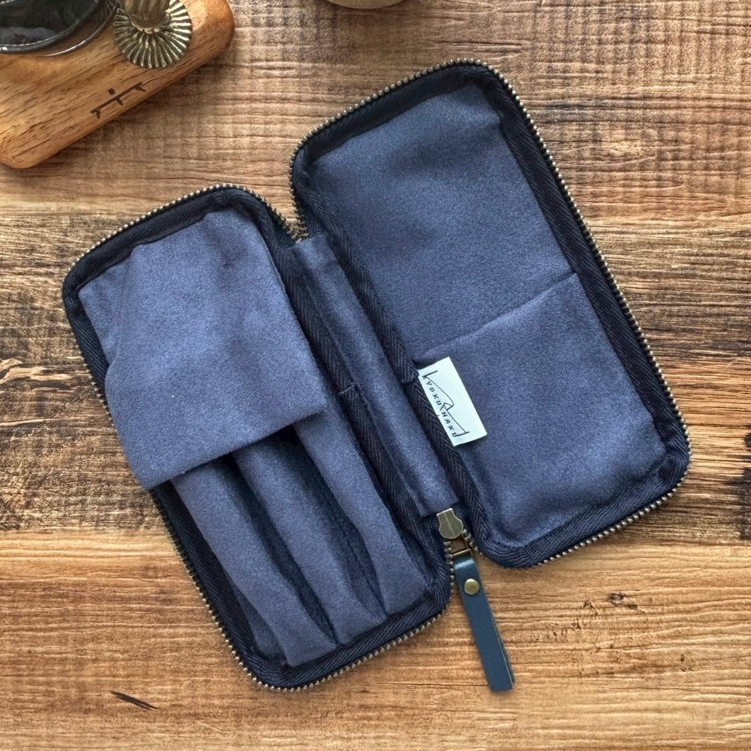 Interior view of three pen case , shown open on a rustic wooden tabletop. 