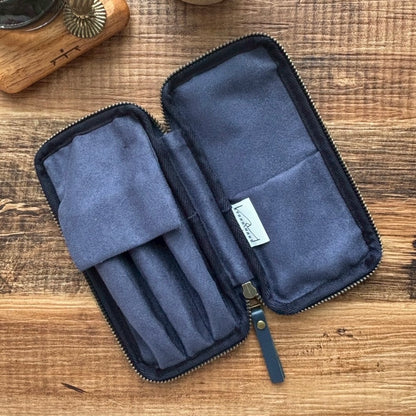 Interior view of three pen case , shown open on a rustic wooden tabletop. 
