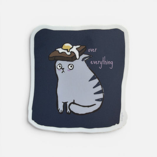 Piper Trading Co. sticker of a grey cat with a fried egg on toast on its head, looking unimpressed.