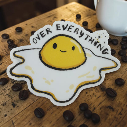 Piper Trading Co. Over Everything sticker featuring a cartoon fried egg with a smiling face and the text "OVER EVERYTHING" in black lettering.