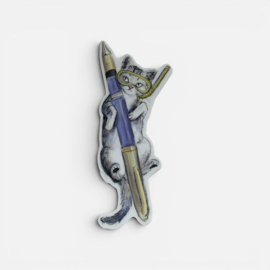 Piper Trading Co. sticker of a grey tabby cat wearing a yellow snorkel mask, holding a blue and gold fountain pen.